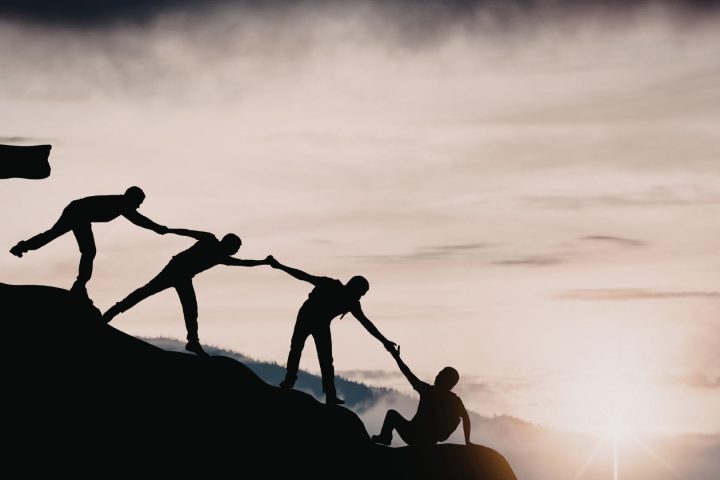 A group of people silhouetted against a sunrise, representing teamwork and connection at the Fiji Educators Conference 2026.